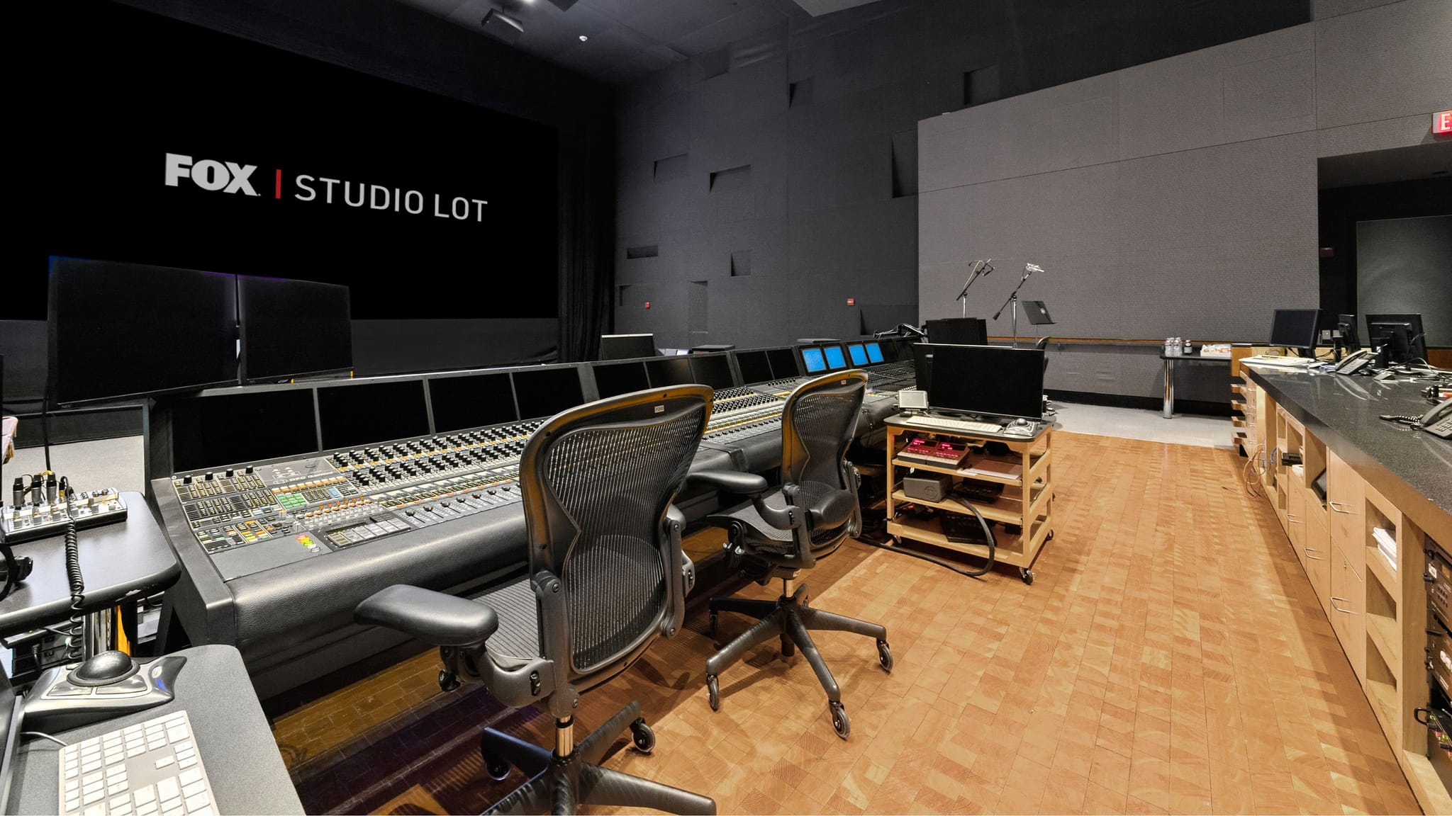 A professional studio control room with a large mixing console and a screen displaying 'FOX | STUDIO LOT'.