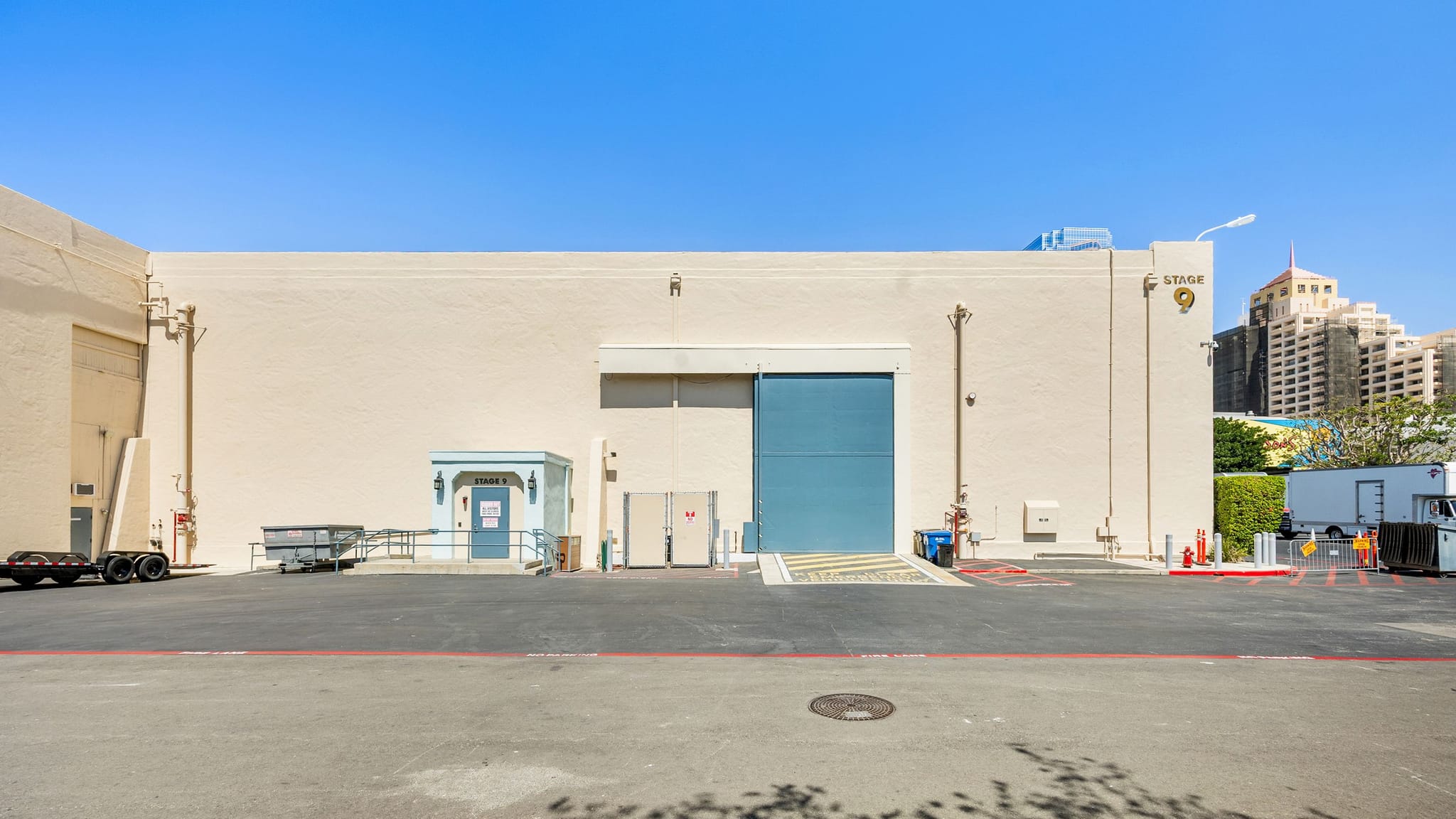 Exterior of Studio 9, a large light-colored building with a blue rolling door, under a clear sky.
