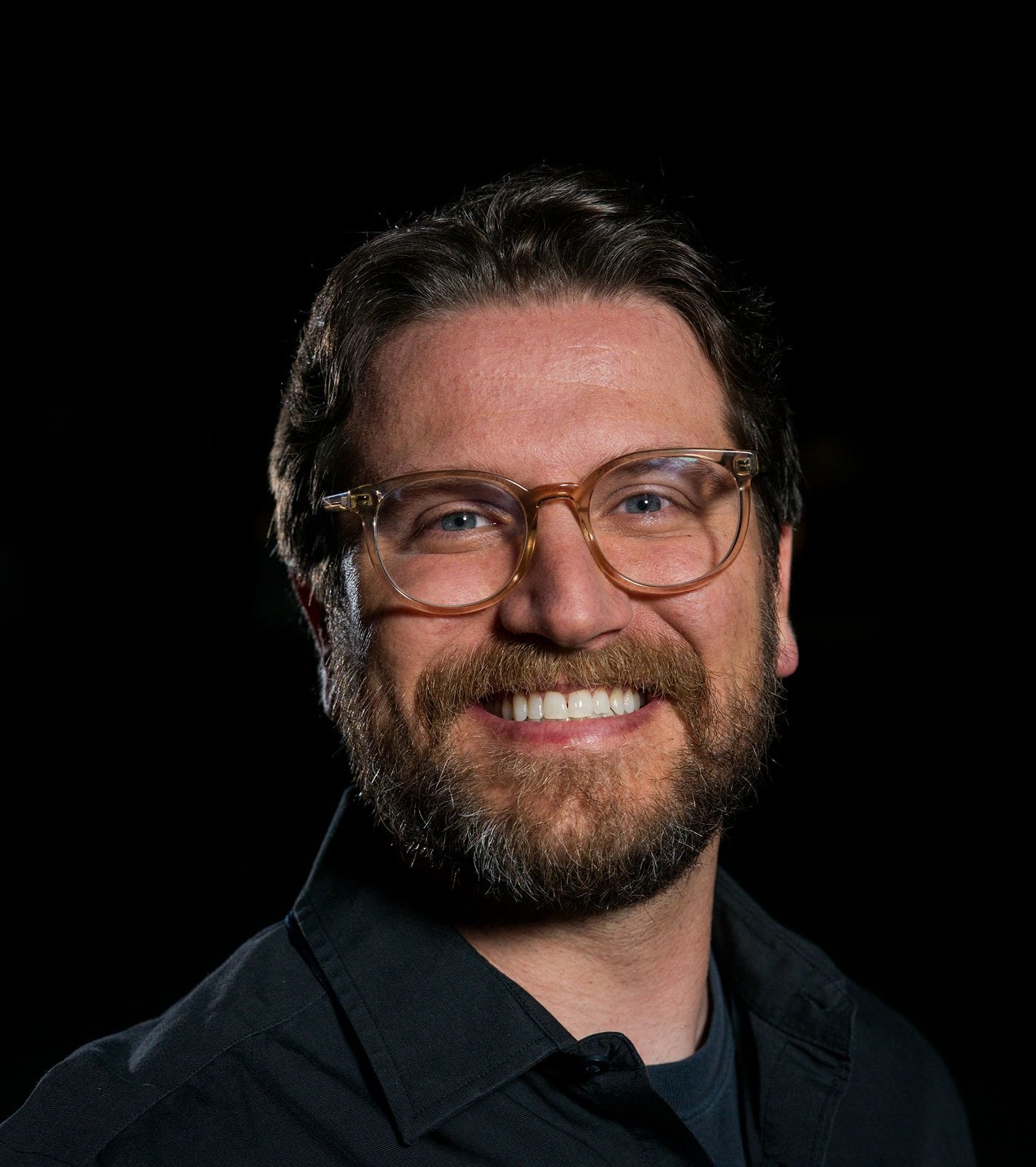 Smiling man with a beard and glasses.