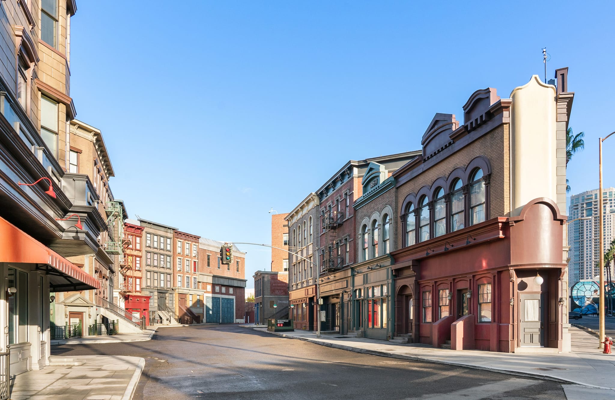 An empty street lined with old-fashioned multi-story buildings under a clear blue sky.