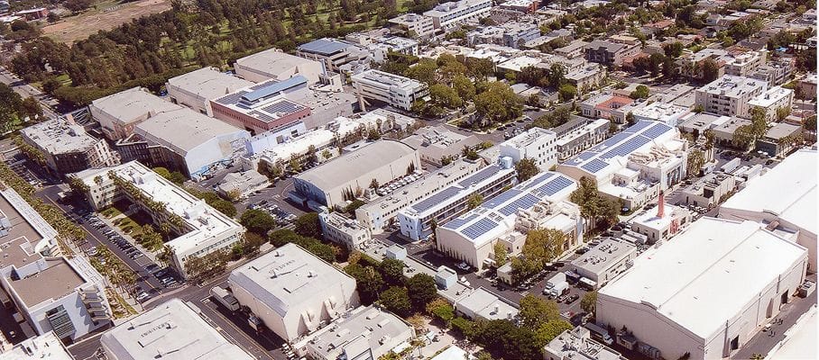 Aerial view of a large studio complex with many buildings, including sound stages and some with solar panels on their roofs.