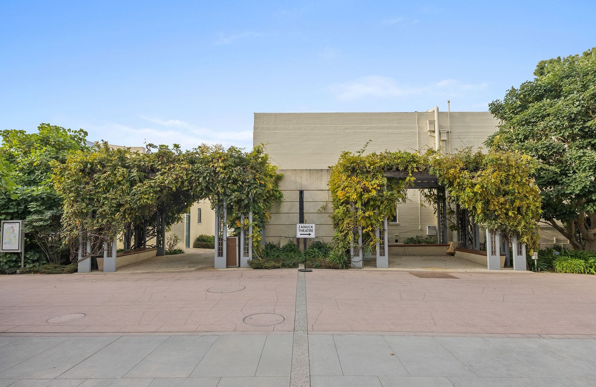 A vine-covered arbor entrance leading to the Children's Theatre Guild building.