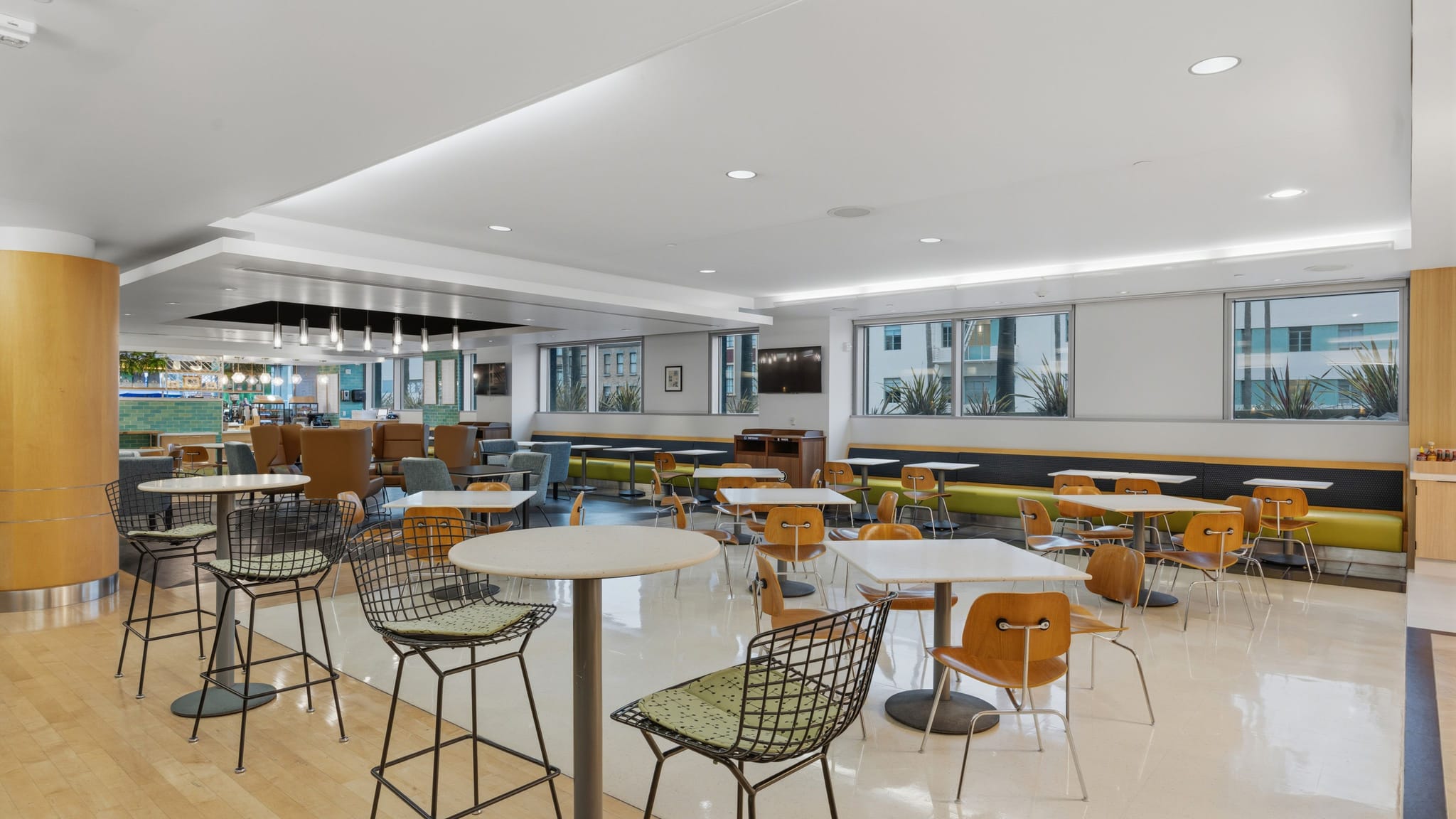 A bright, modern common area with diverse seating including high-top tables, standard tables, and bench seating.