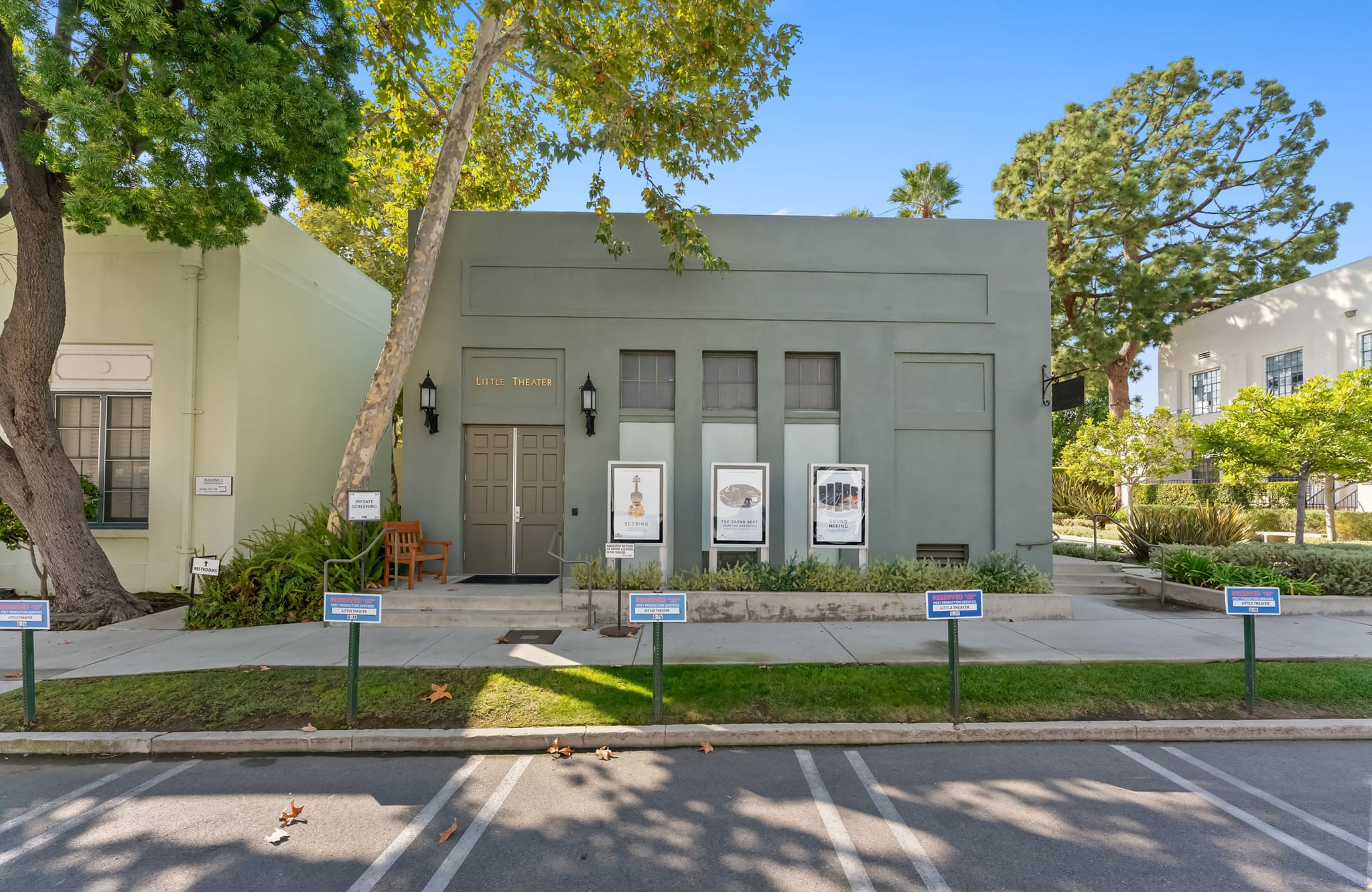 Exterior view of the Griffin Theater, a muted green building with show posters displayed outside, flanked by trees.