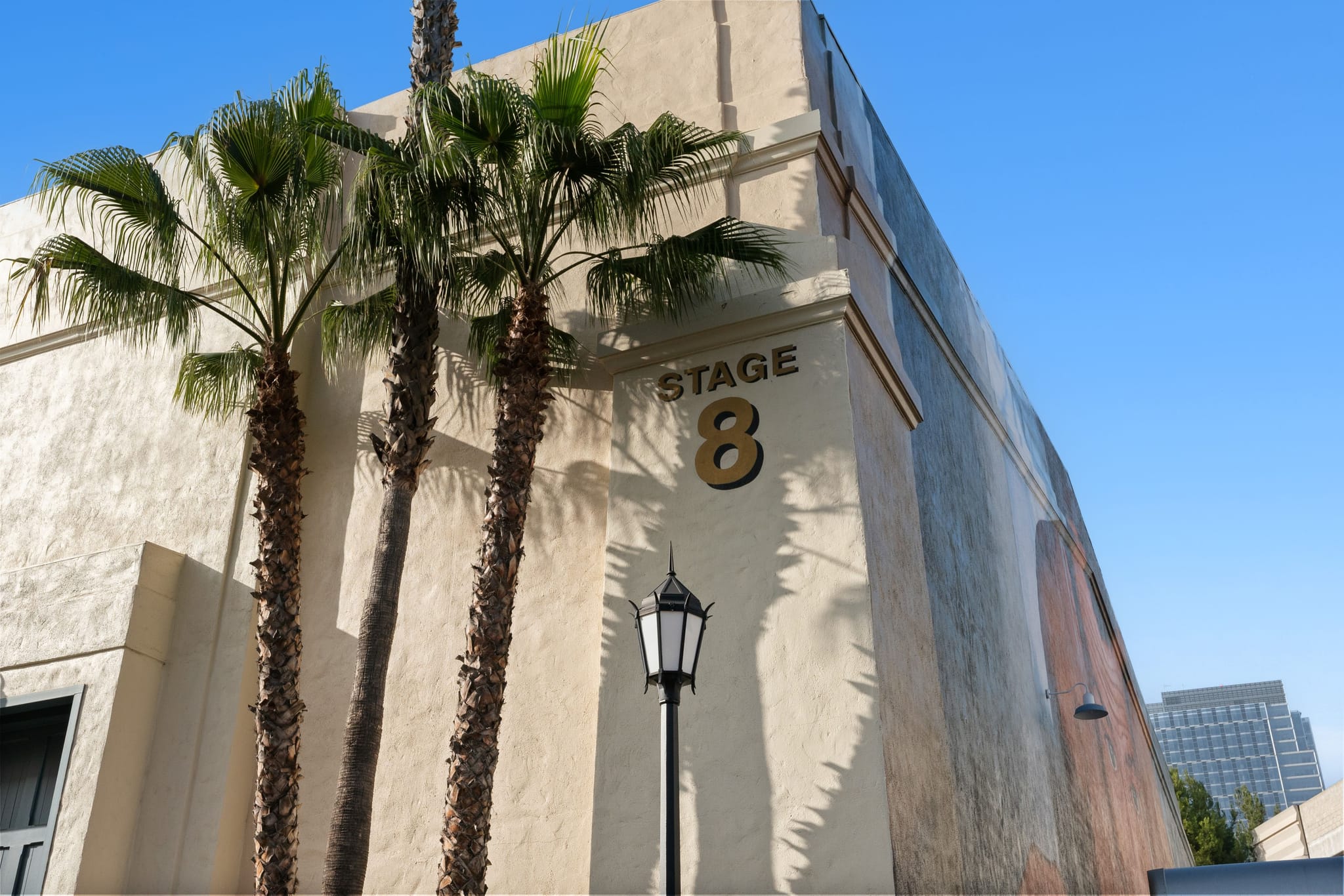 Studio building labeled 'STAGE 8' with three palm trees and a lamppost.