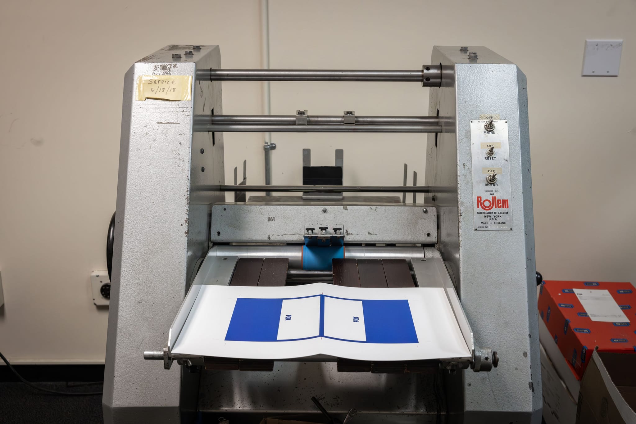 A ROLlem industrial machine with a sheet of paper displaying blue rectangles on its feed tray.