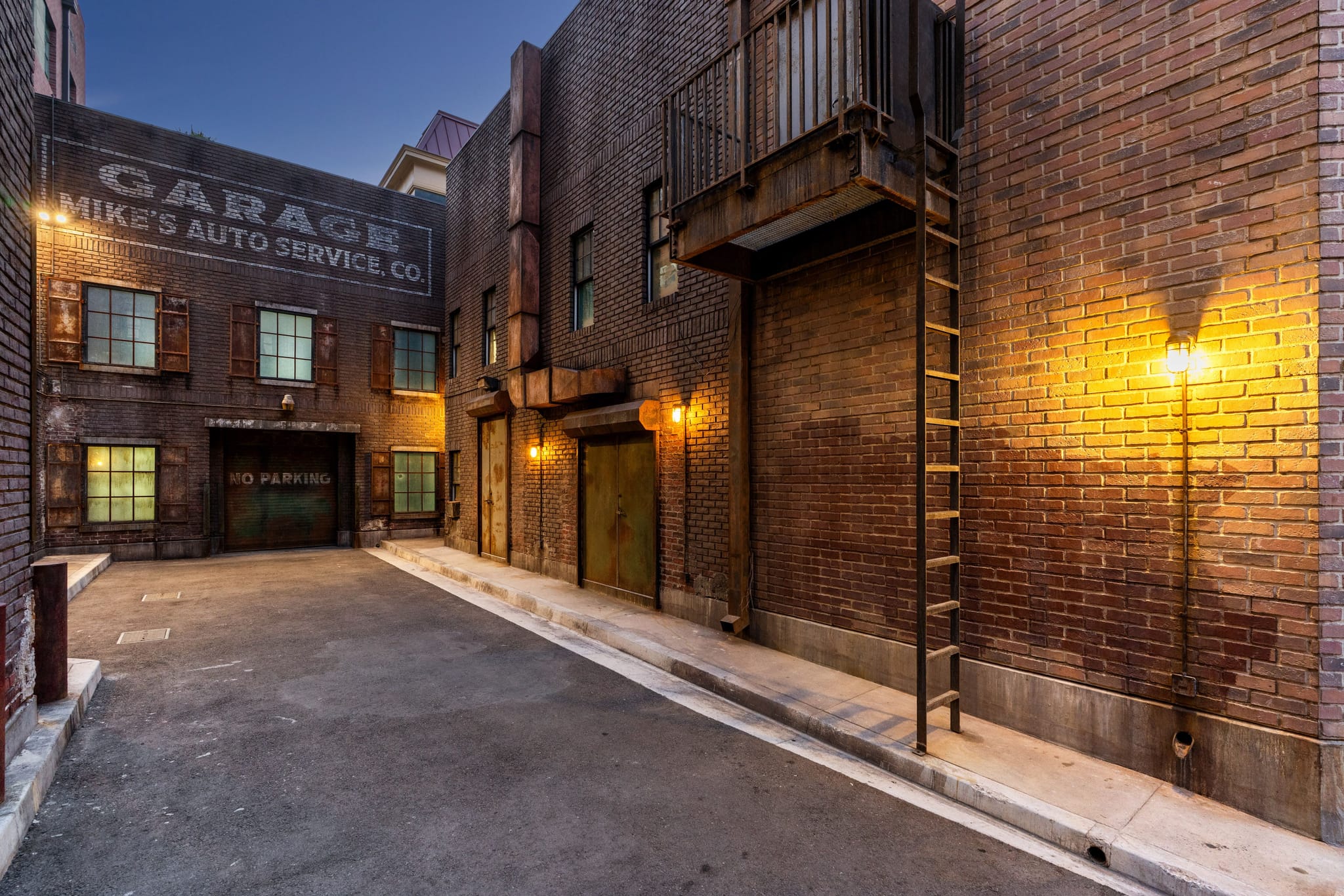 Old brick alleyway illuminated by warm wall lights, with a "Mike's Auto Service Co. Garage" sign.