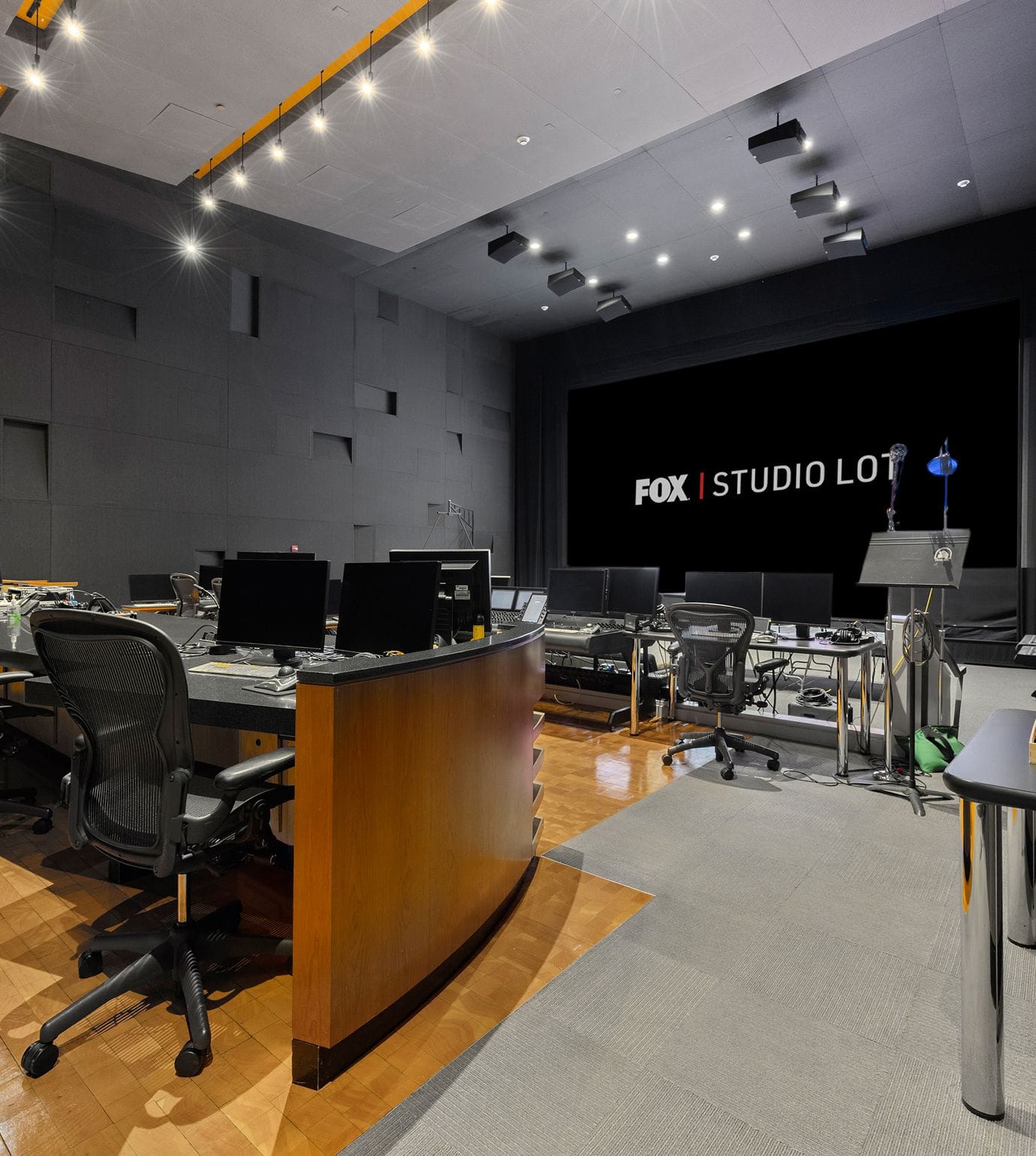 A professional broadcast control room with multiple workstations and a large screen displaying "FOX | STUDIO LOT".