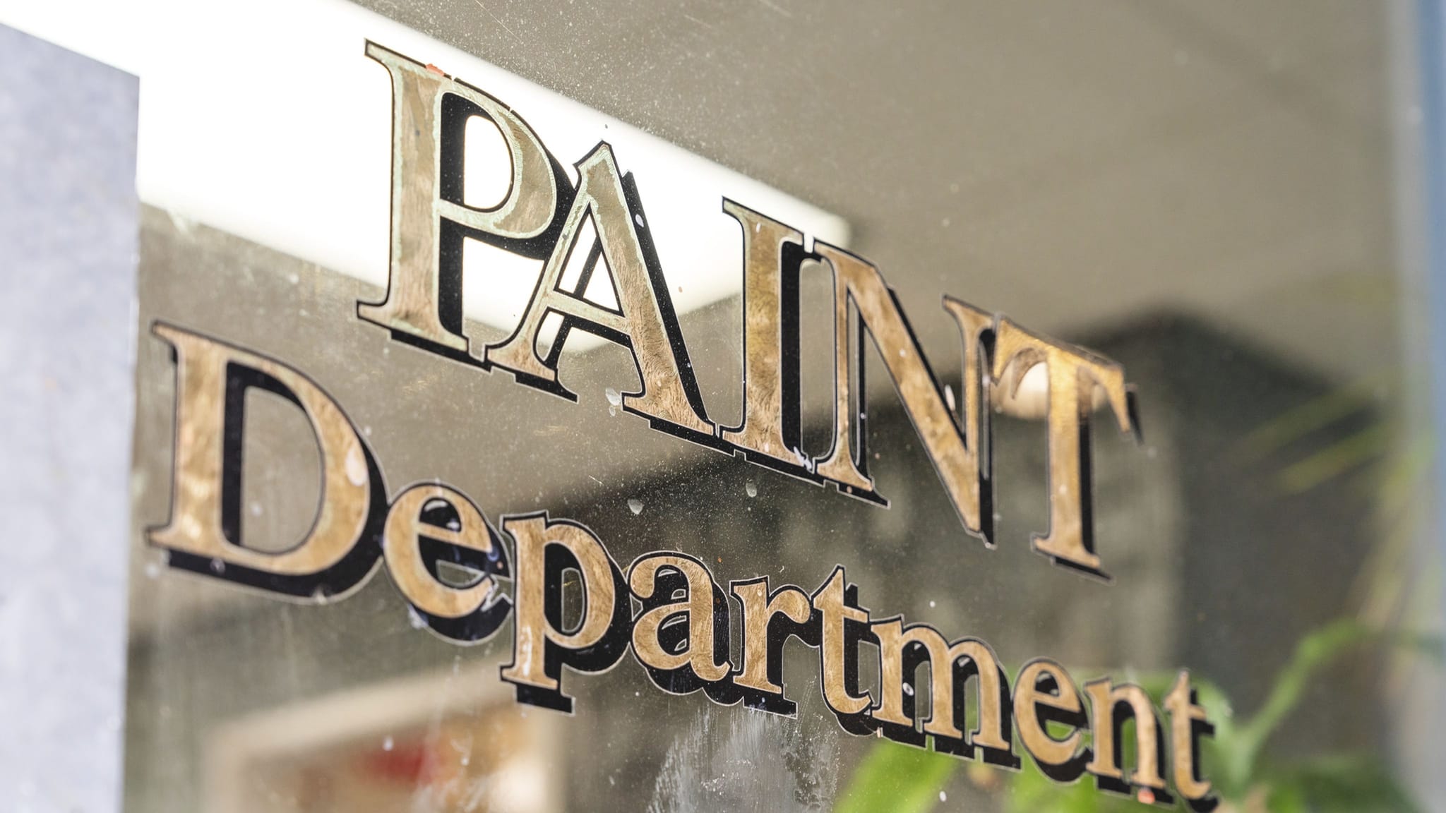 Vintage gold "PAINT Department" sign on glass.