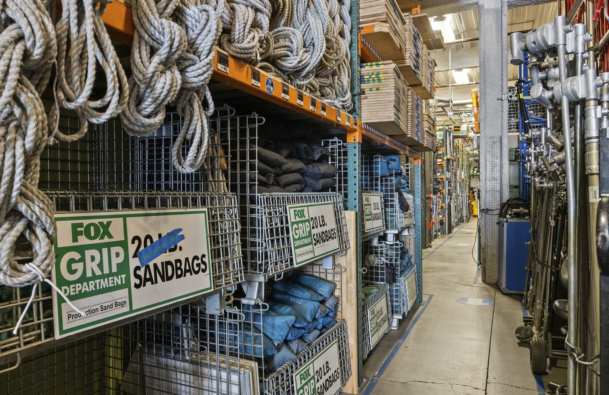 Warehouse aisle filled with coils of rope, Fox Grip sandbags, and production grip equipment.