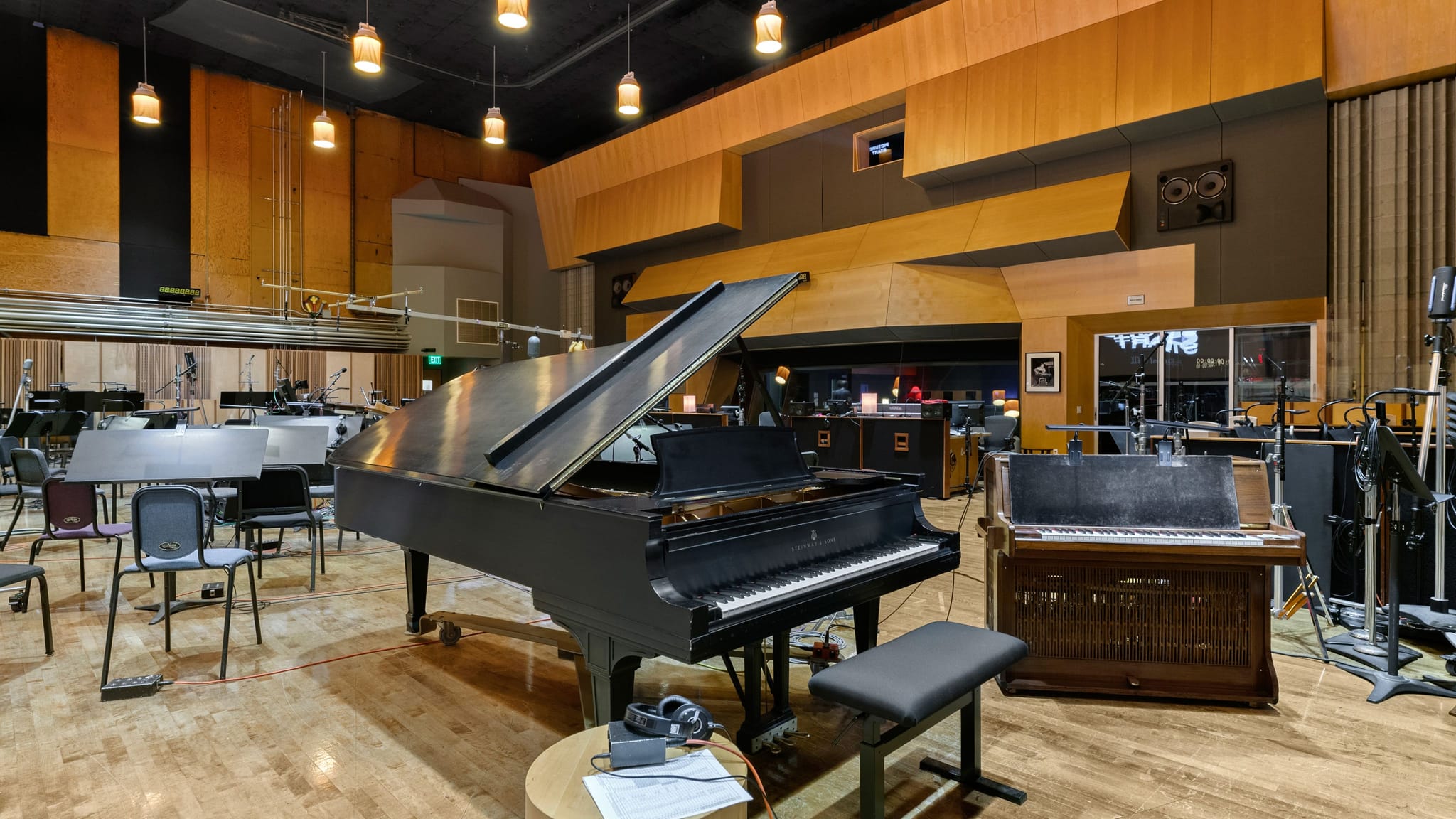 A recording studio with a grand piano, an organ, music stands, and audio recording equipment.