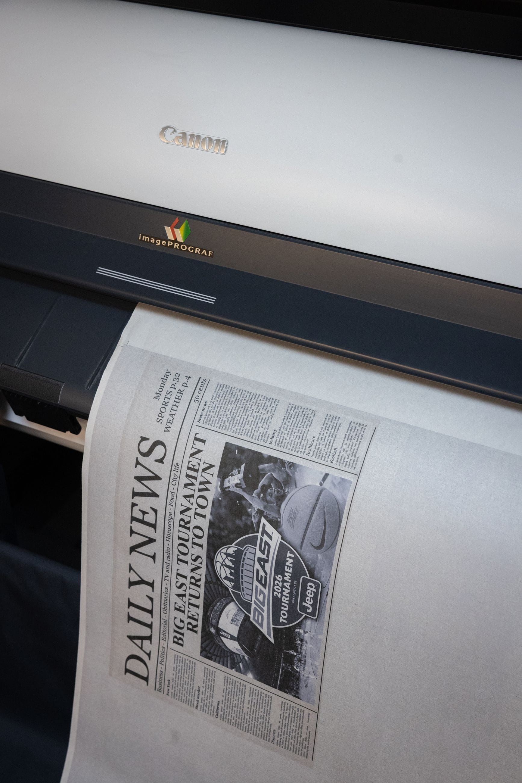 A Canon imagePROGRAF printer outputs a newspaper print with a 'DAILY NEWS' headline about the Big East Tournament.