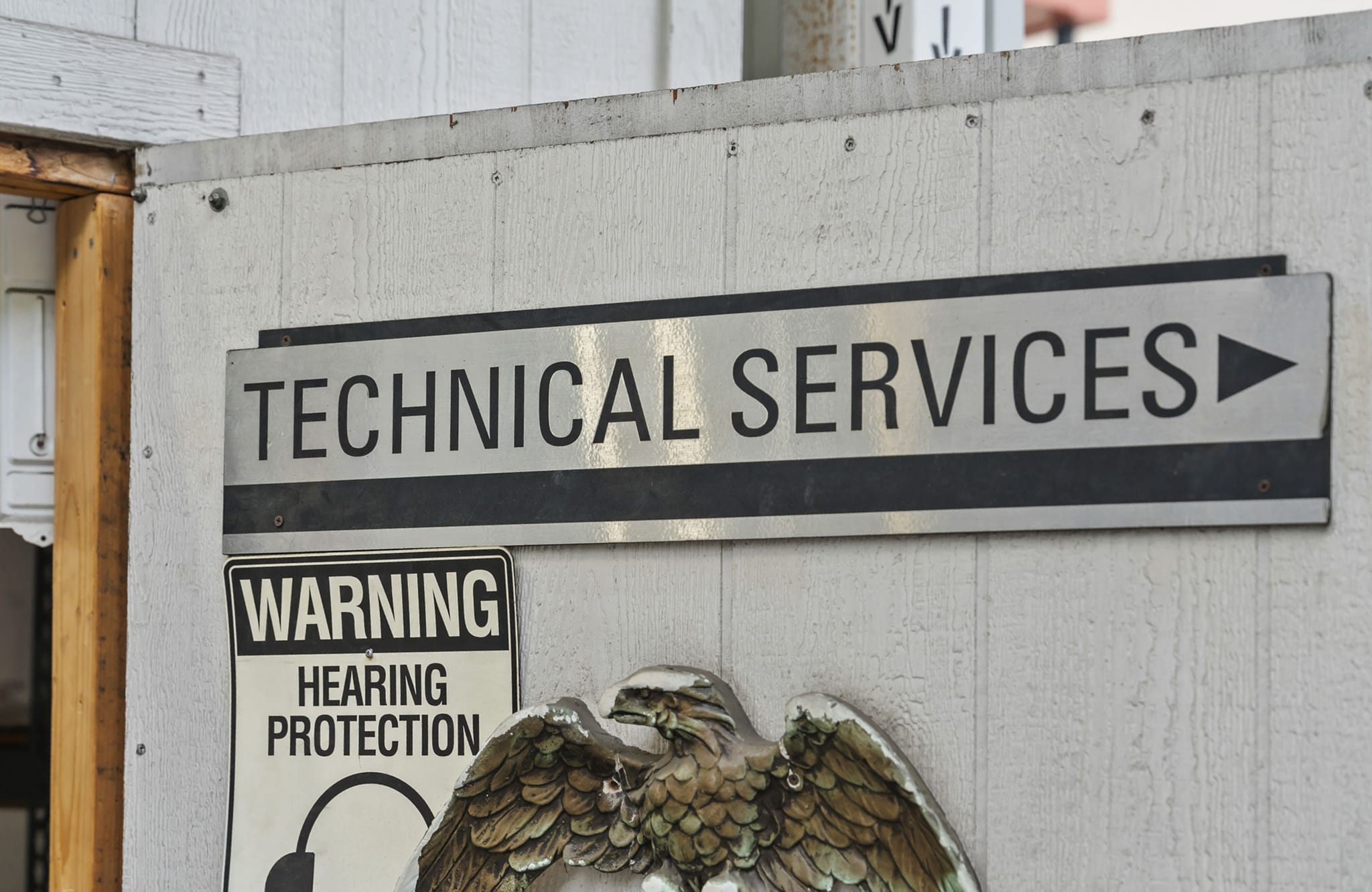 A sign reads "TECHNICAL SERVICES" with a right arrow, above a "WARNING HEARING PROTECTION" sign.