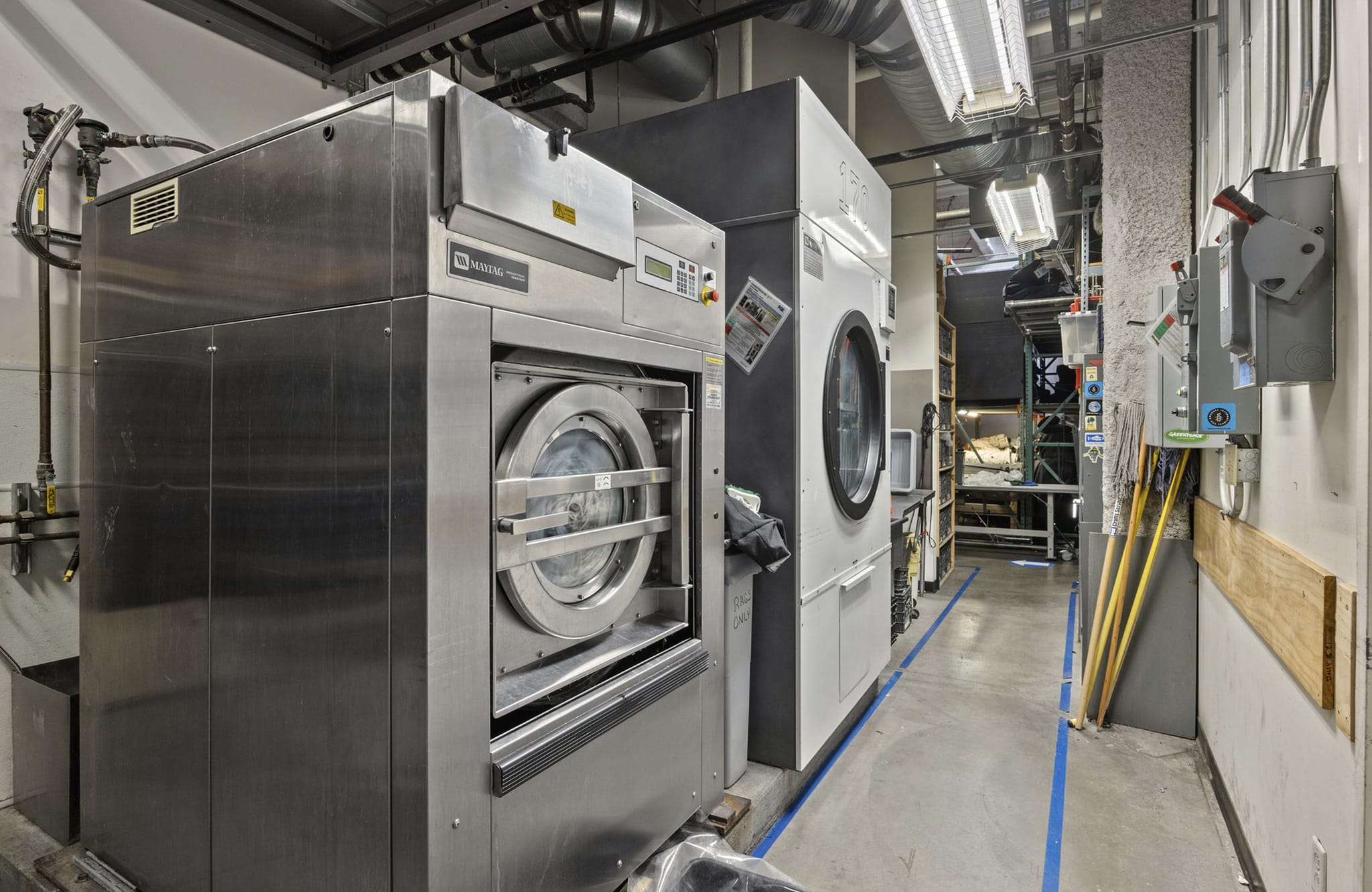 Industrial laundry room with large stainless steel machines.