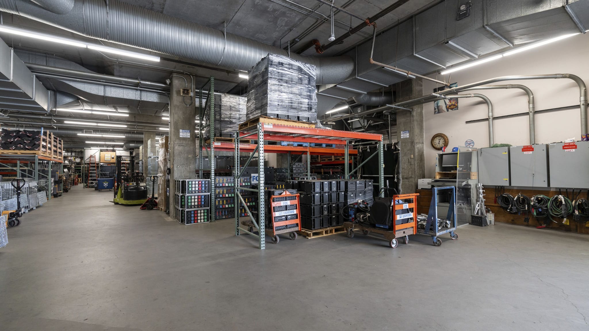 A bustling warehouse filled with stacked items on shelves, a forklift, and a work area.